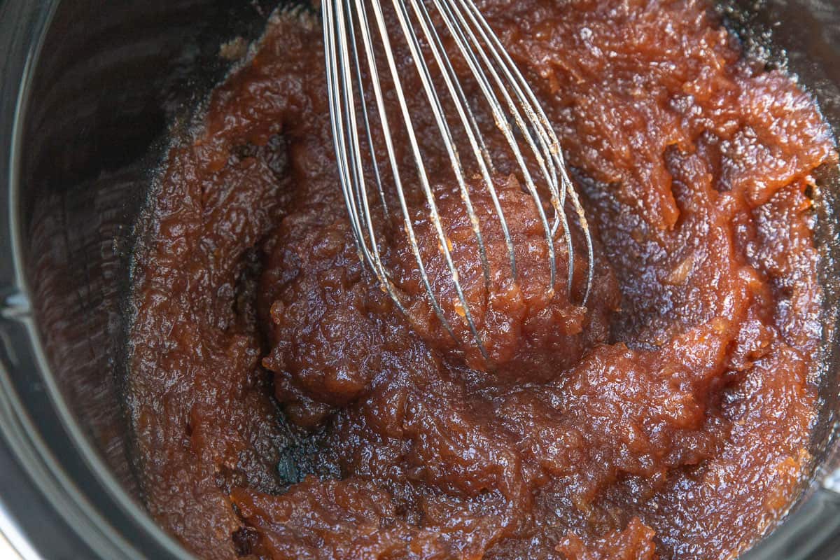 apple butter in a crockpot with a whisk.