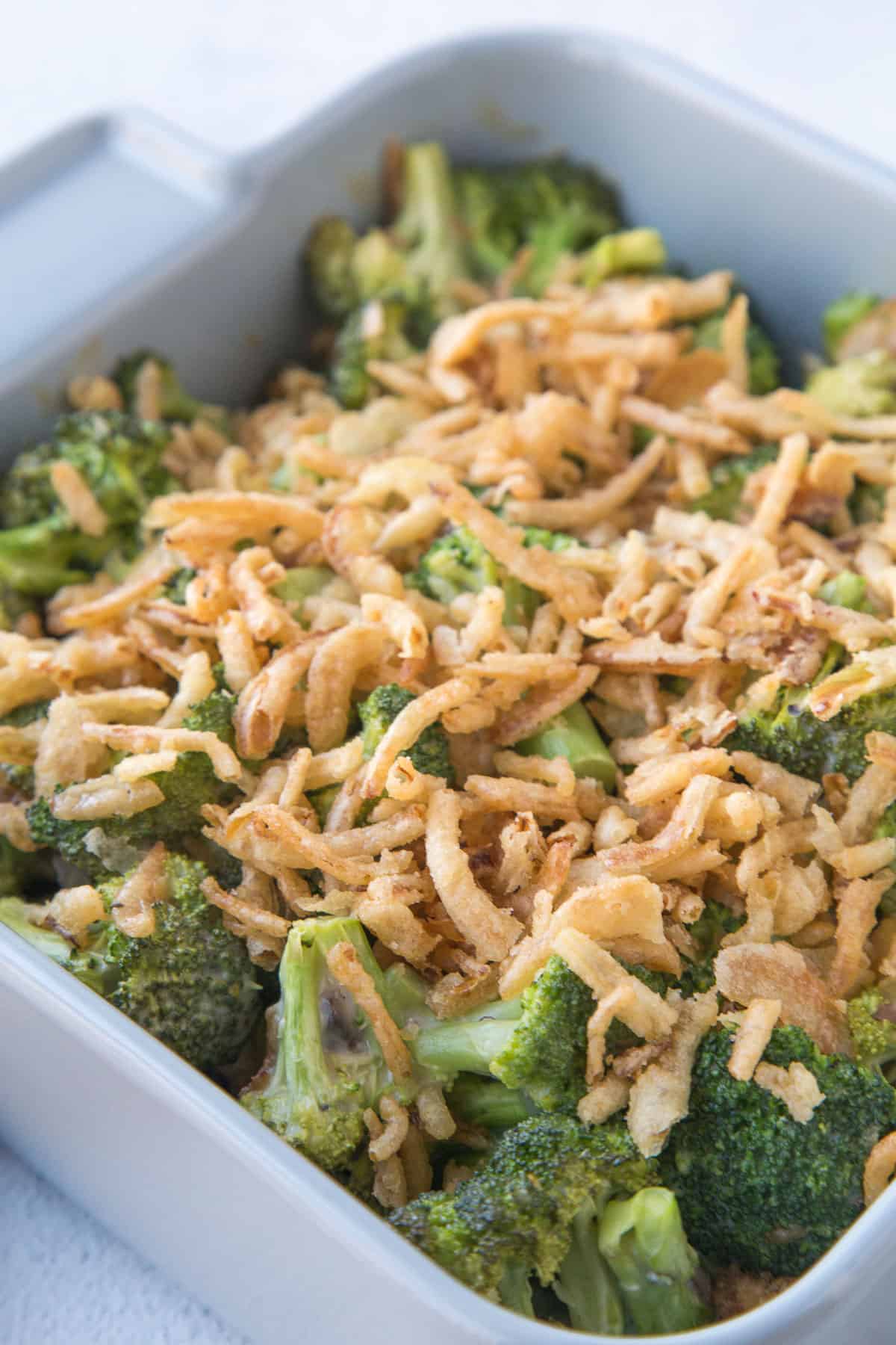 broccoli casserole with fried onions on top in a gray casserole dish. 