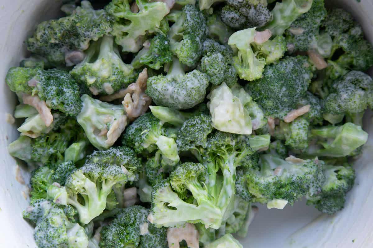 broccoli coated in a creamy sauce in a white bowl.