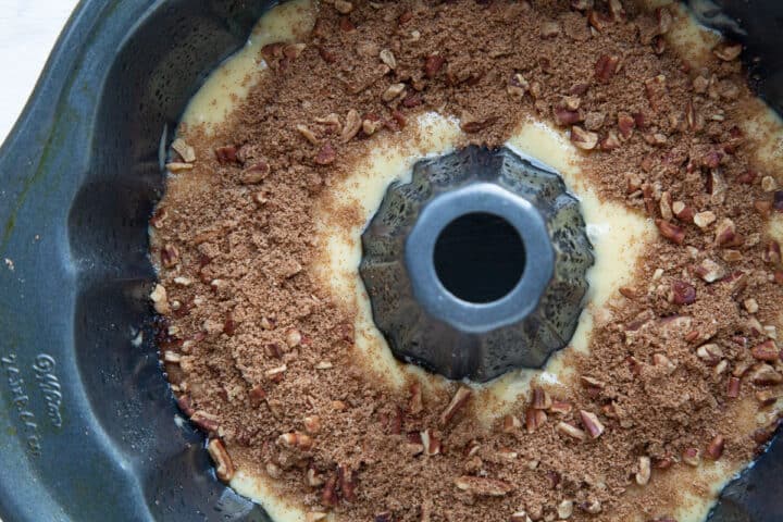 cake batter topped with a pecan and brown sugar mixture in a bundt pan.