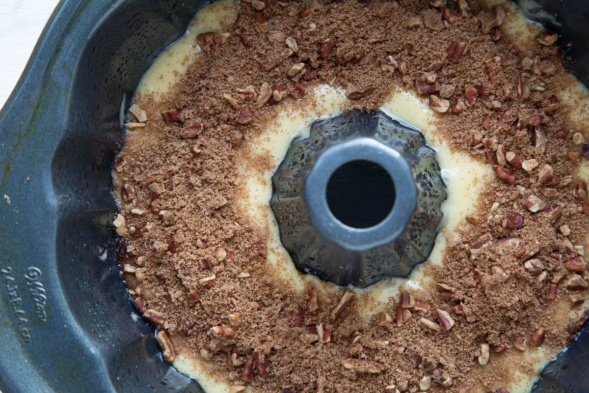 cake batter topped with a pecan and brown sugar mixture in a bundt pan.
