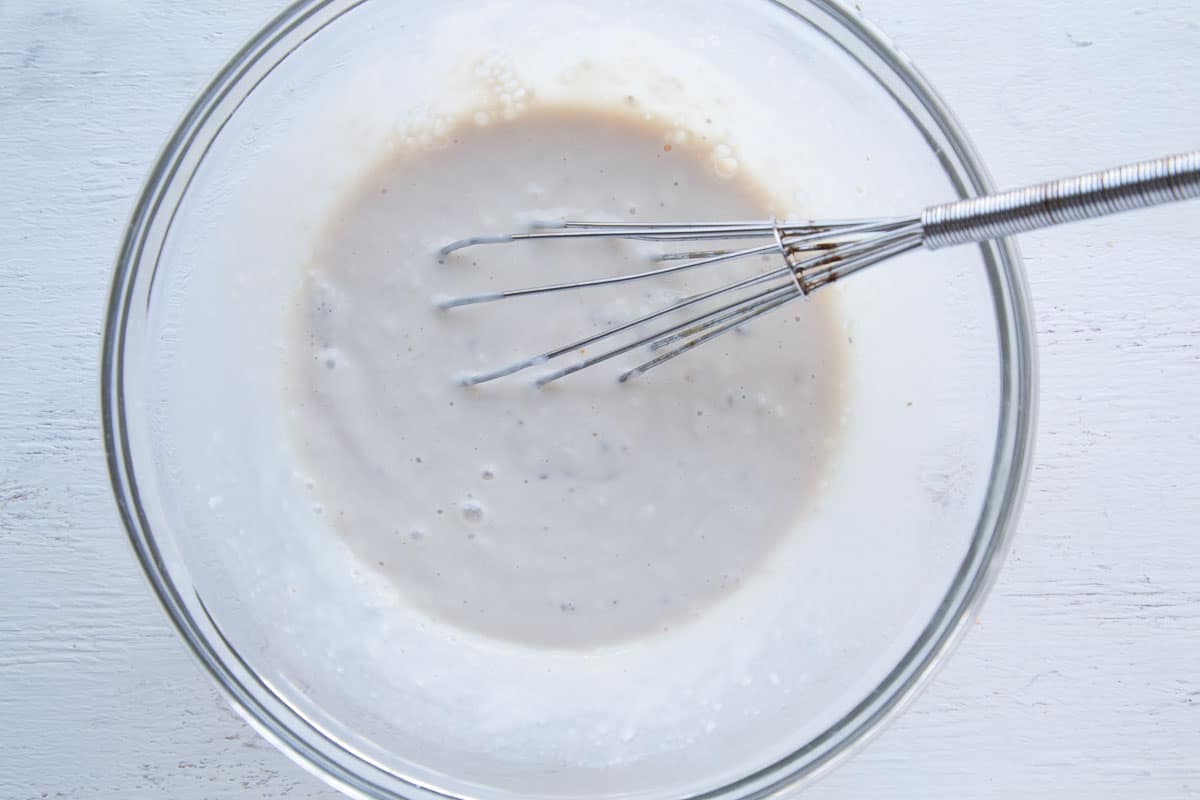 cream of mushroom soup and a whisk in a glass bowl.