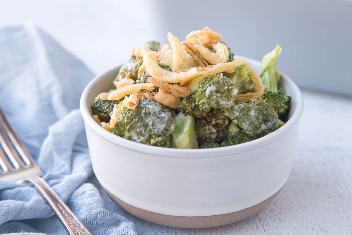 broccoli casserole in a small round dish, topped with fried onions.