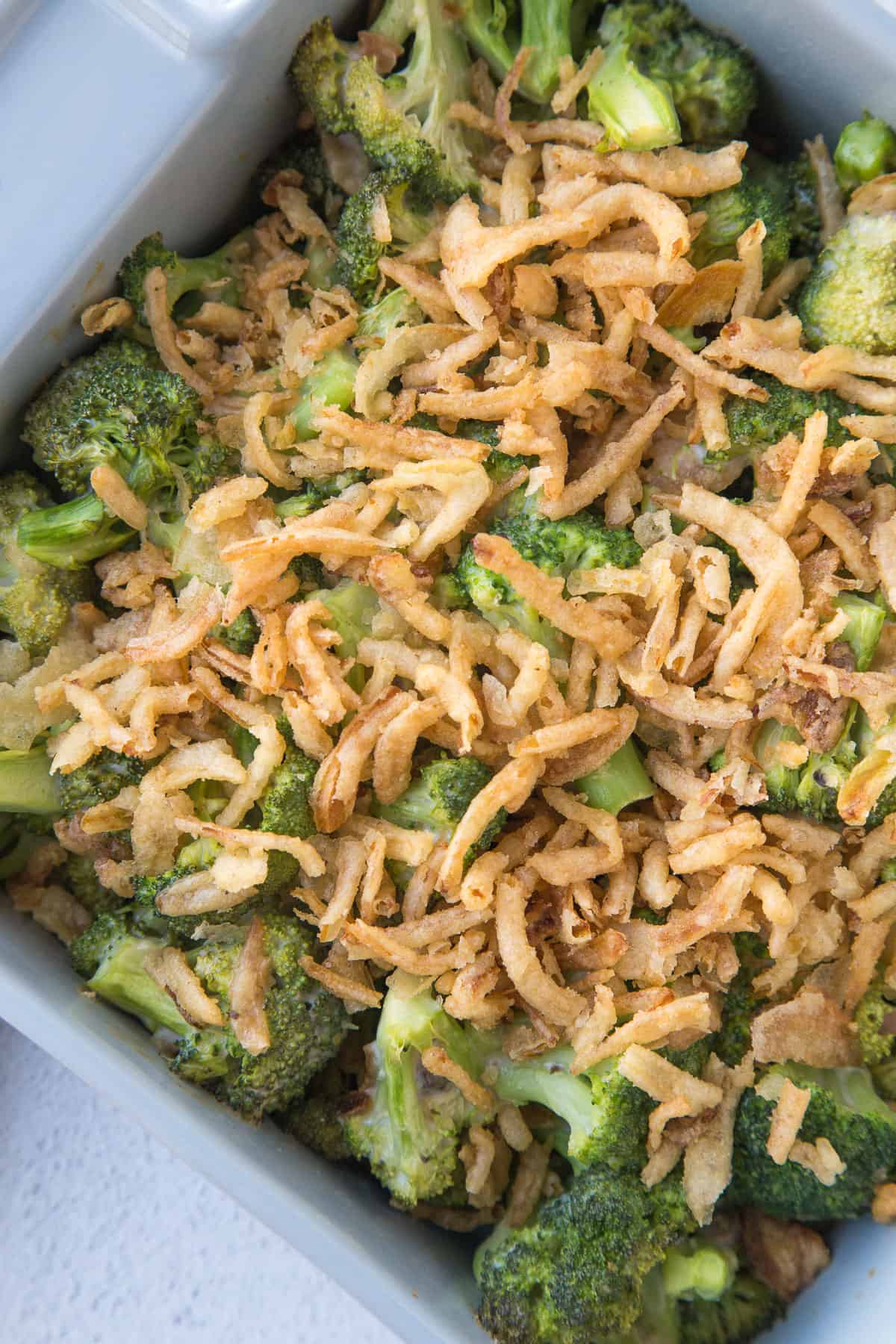 broccoli casserole in a gray casserole dish topped with fried onions.
