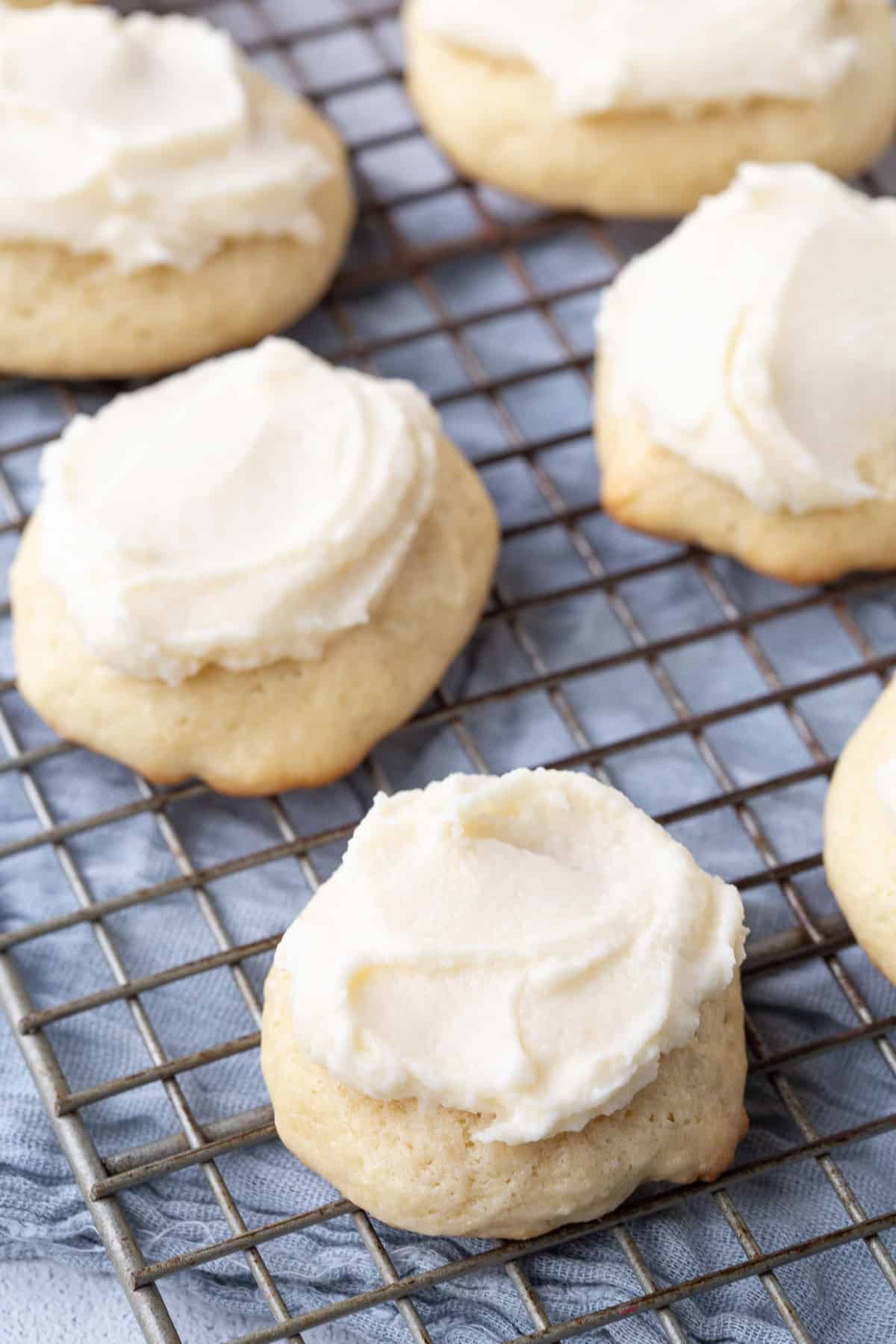 sour cream cookies topped with frosting on a wire rack.