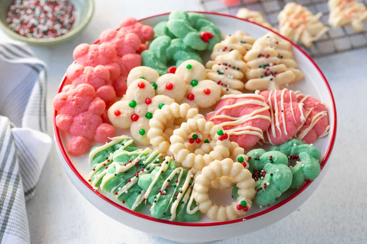 white platter with a red rim filled with colorful spritz cookies.