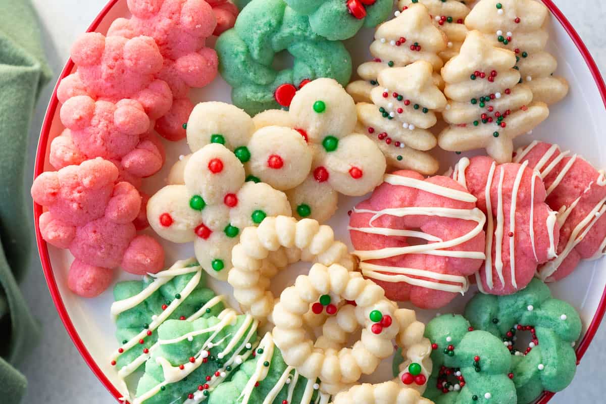 red, green, and white spritz cookies decorated with sprinkles and white chocolate.