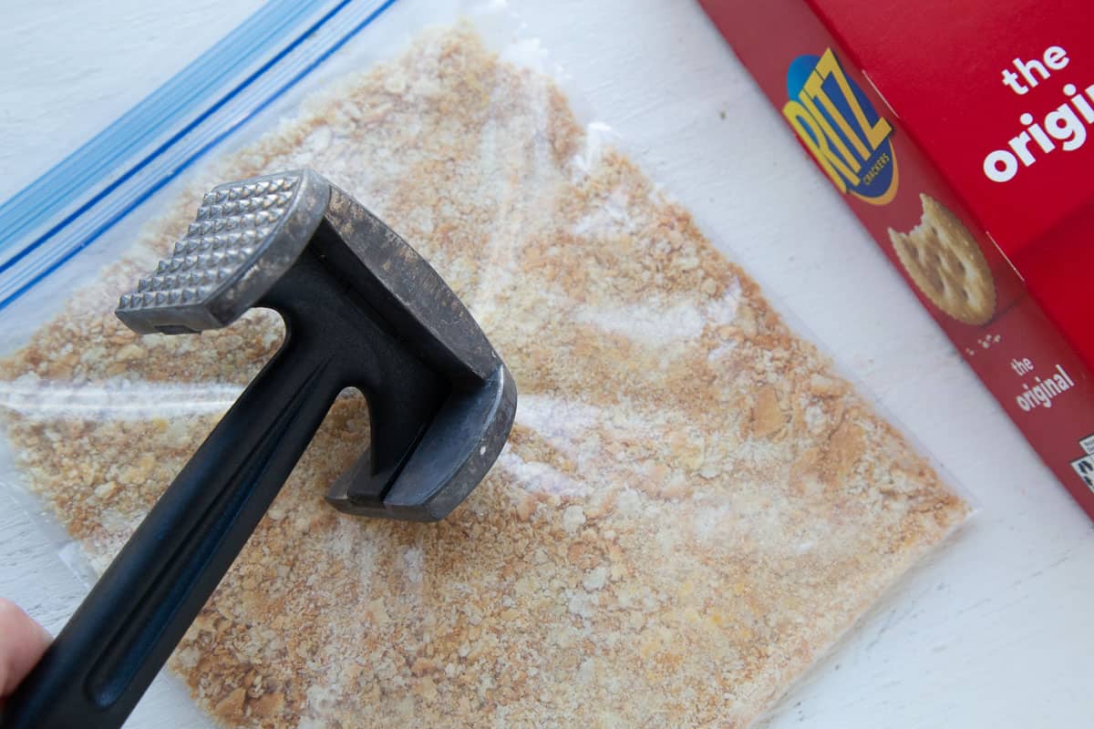 meat mallet pounding a plastic bag filled with ritz cracker crumbs.