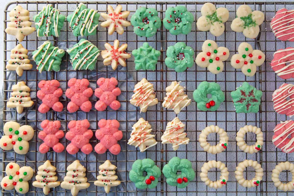 a variety of plain and decorated spritz cookies on a wire rack.
