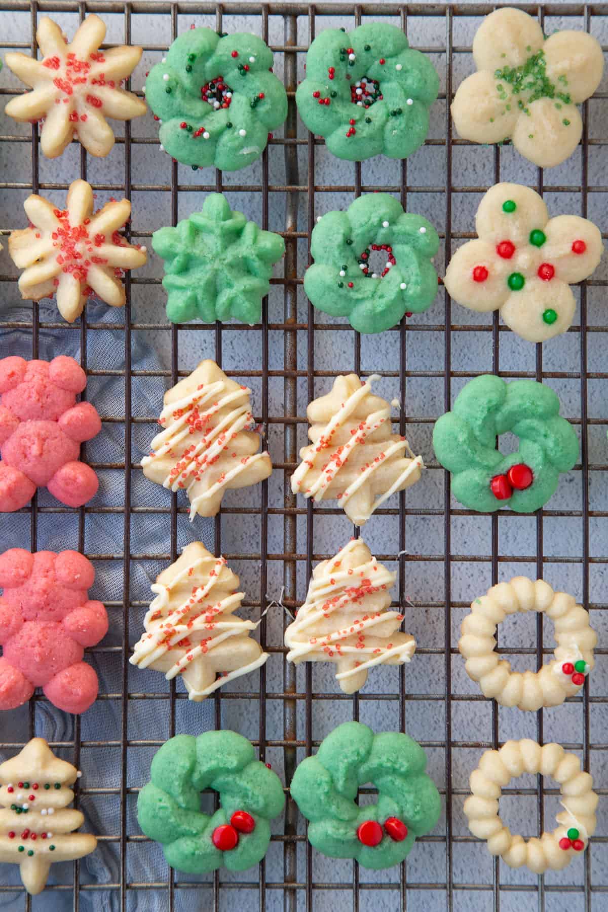 a variety of plain and decorated old fashioned spritz cookies on a wire rack.