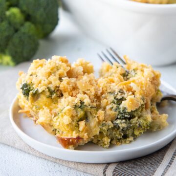 scoop of cheesy velveeta broccoli casserole topped with ritz cracker crumbs on a white plate.