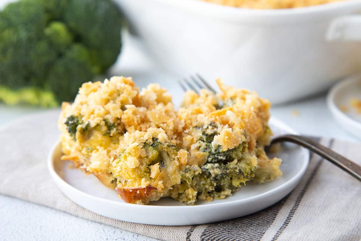 broccoli casserole on a white plate with a fork. 