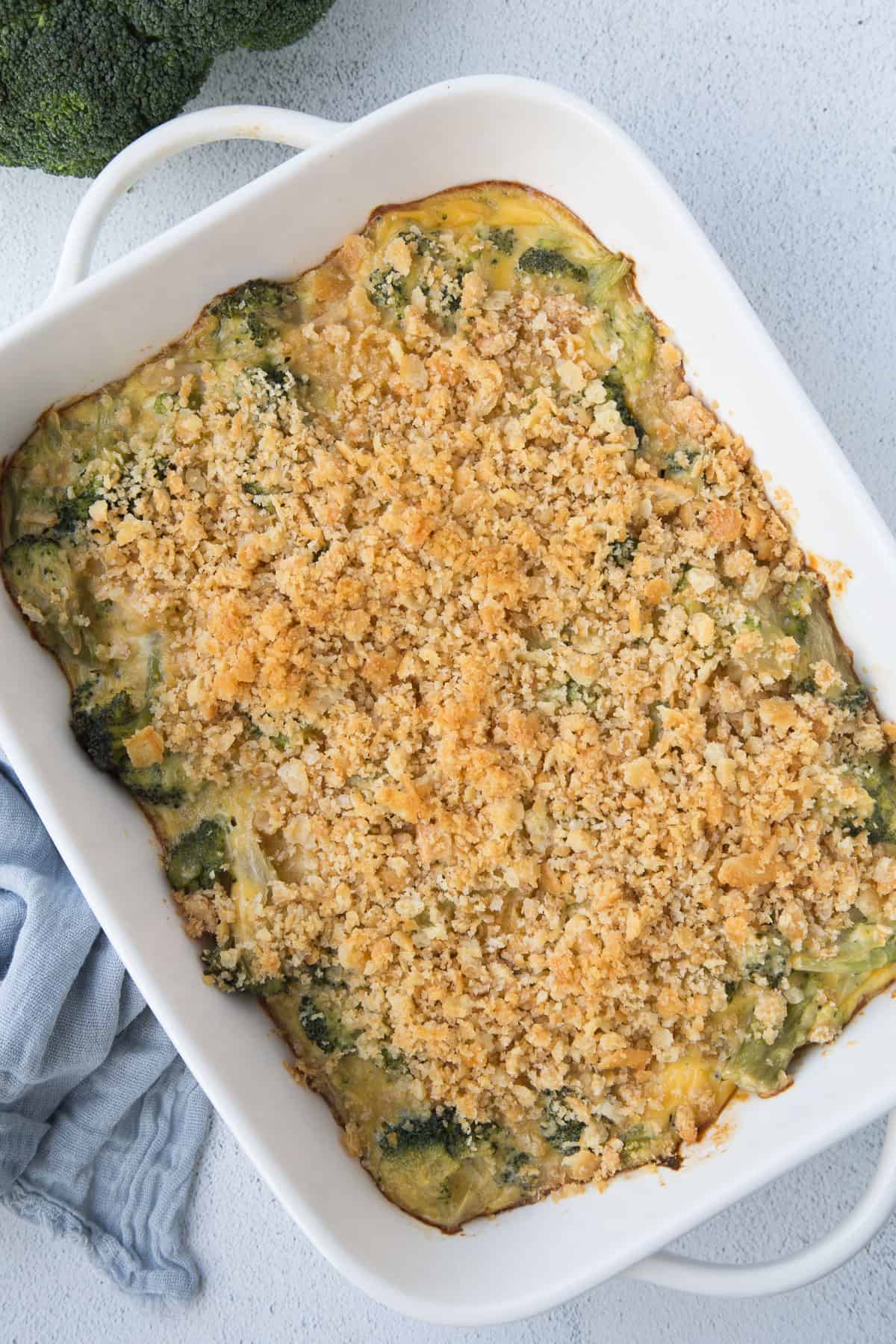 velveeta broccoli casserole topped with ritz cracker crumbs in a white casserole dish.