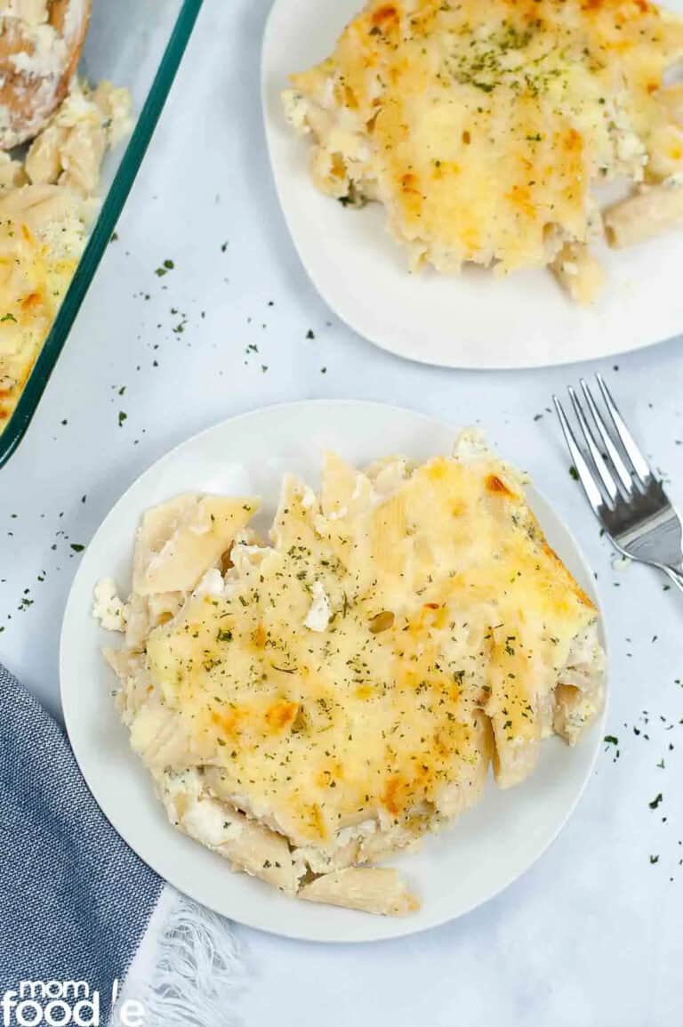 ziti alfredo on two white plates next to a fork.