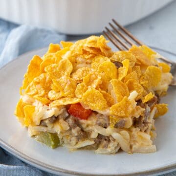 slice of hash brown casserole topped with corn flakes on a white plate.