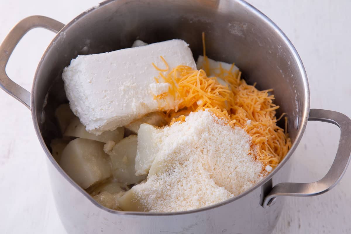 potatoes, cream cheese, cheddar, and parmesan in a large pot.
