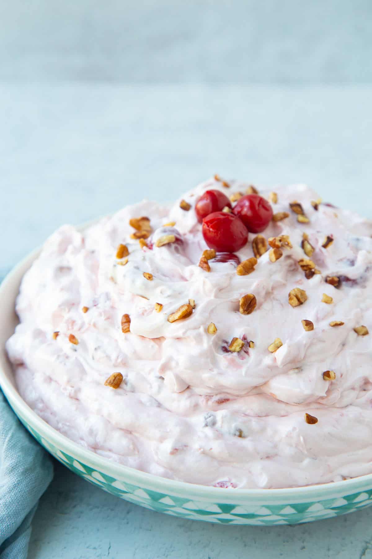 large bowl of cherry salad topped with chopped pecans and cherries.