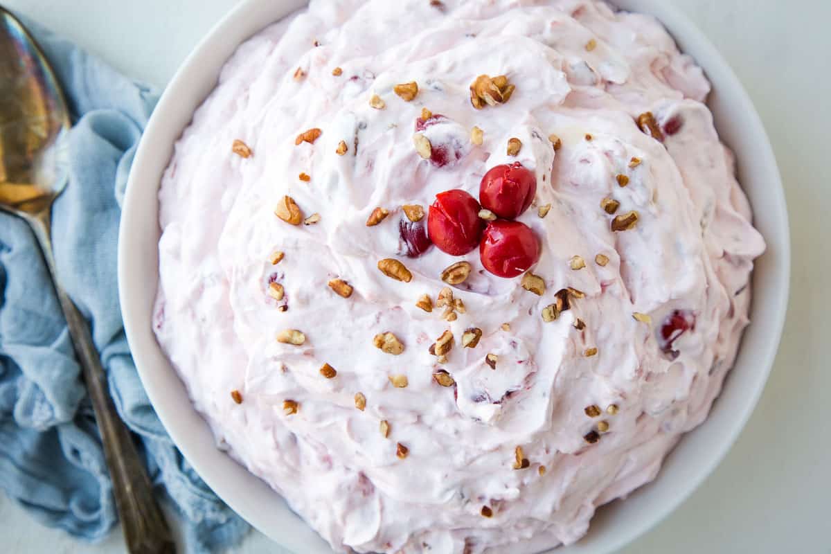 cherry salad in a large low bowl, topped with pecans and cherries.