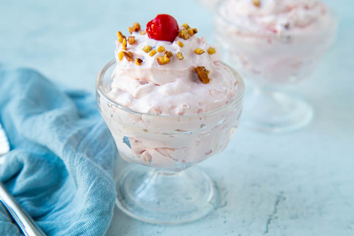 mini glass parfait dish filled with cherry salad, topped with pecans and a cherry.