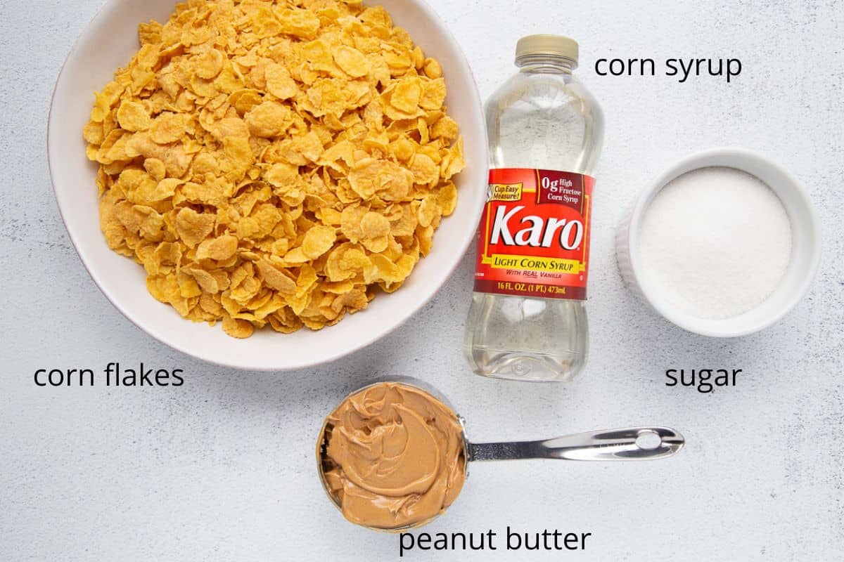 corn flakes, peanut butter, corn syrup, and sugar on a white table.