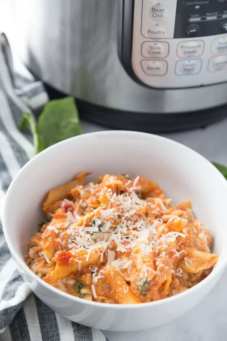 baked ziti in a white bowl next to an instant pot.