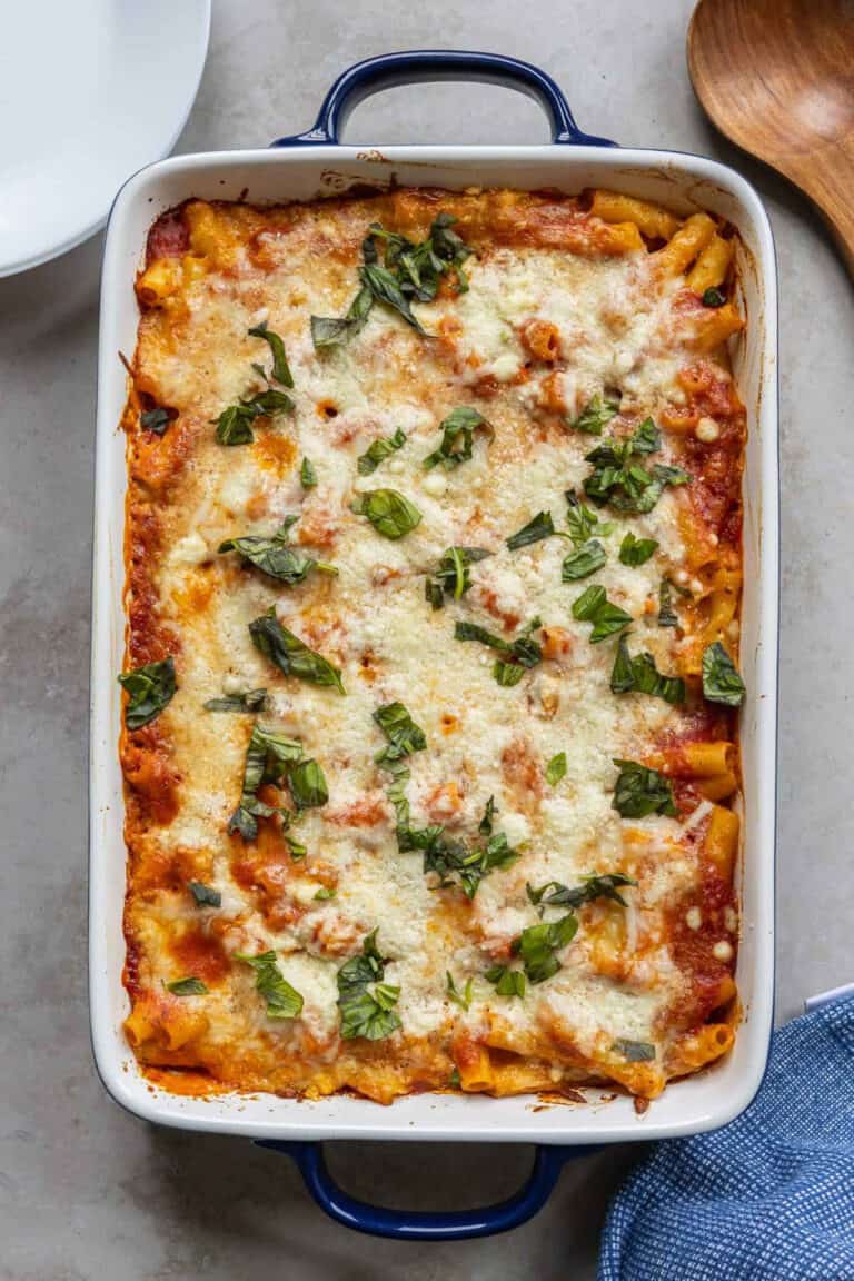 whole casserole dish filled with baked ziti, topped with torn basil.