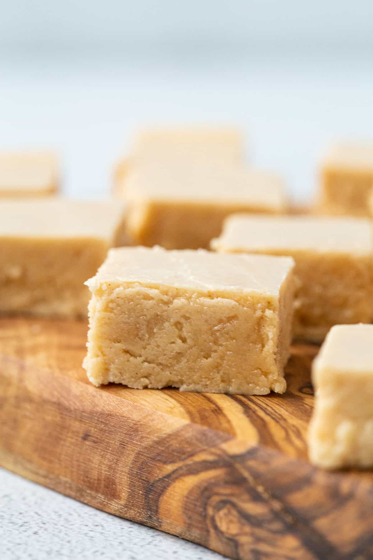 square pieces of peanut butter fudge on a wooden serving board.