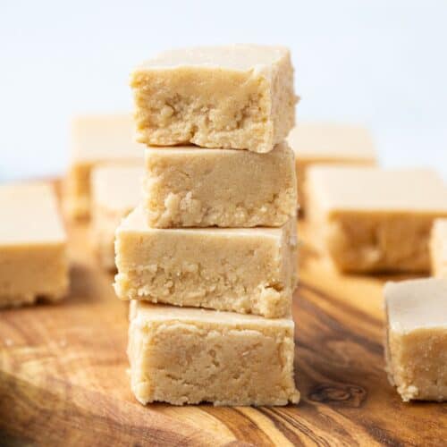 four pieces of peanut butter fudge stacked on top of each other on a wooden serving tray.