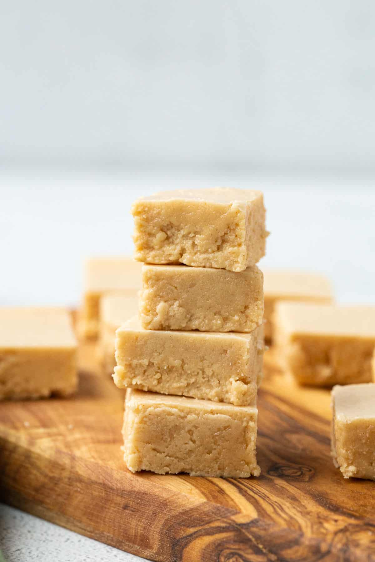 stack of four pieces of peanut butter fudge on a wooden serving tray. 