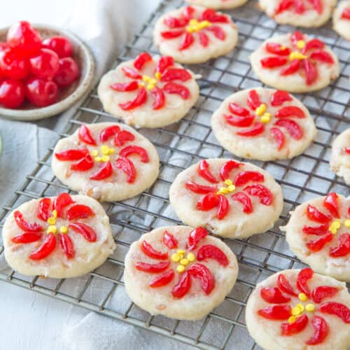 poinsettia cookies made with maraschino cherries on a wire rack.