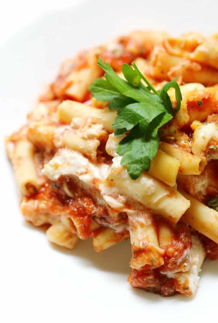 bowl full of baked ziti topped with fresh parsley.