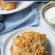 baked chicken thigh on a small white plate next to a platter full of more chicken thighs.