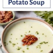 bowl of potato soup topped with chopped bacon and parsley.