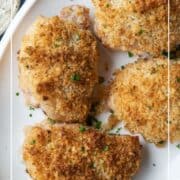 ranch chicken thighs topped with breadcrumbs on a white platter.