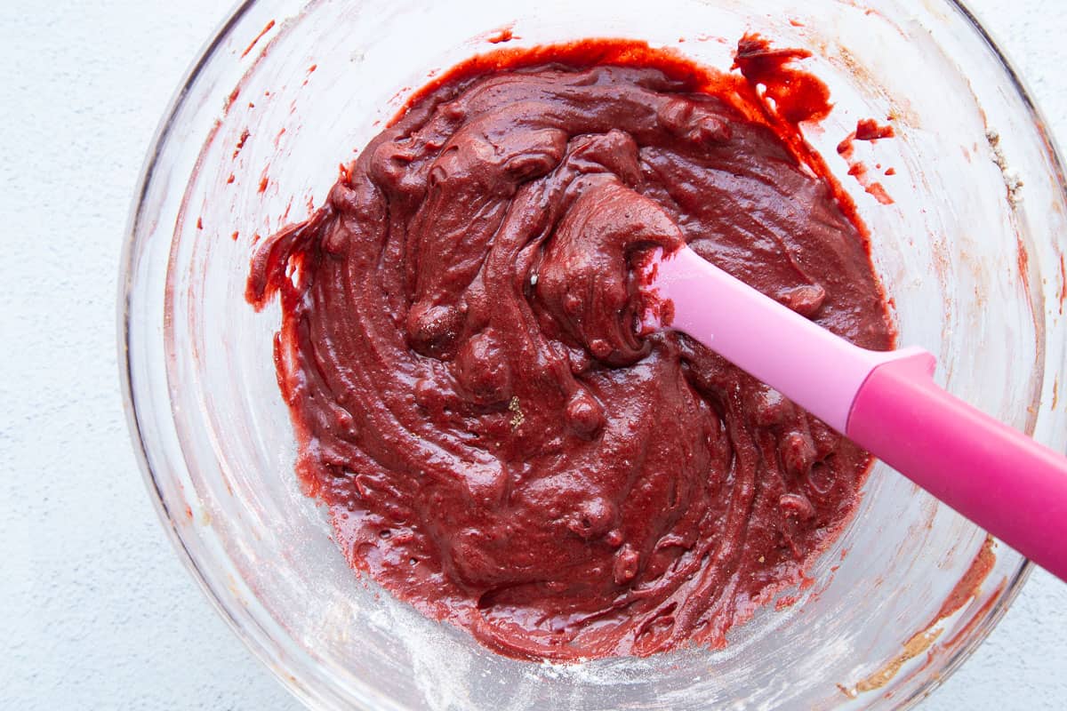 red velvet brownie batter in a glass bowl with a pink spatula.
