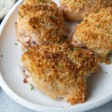 breadcrumb topped ranch chicken thighs on a white platter.
