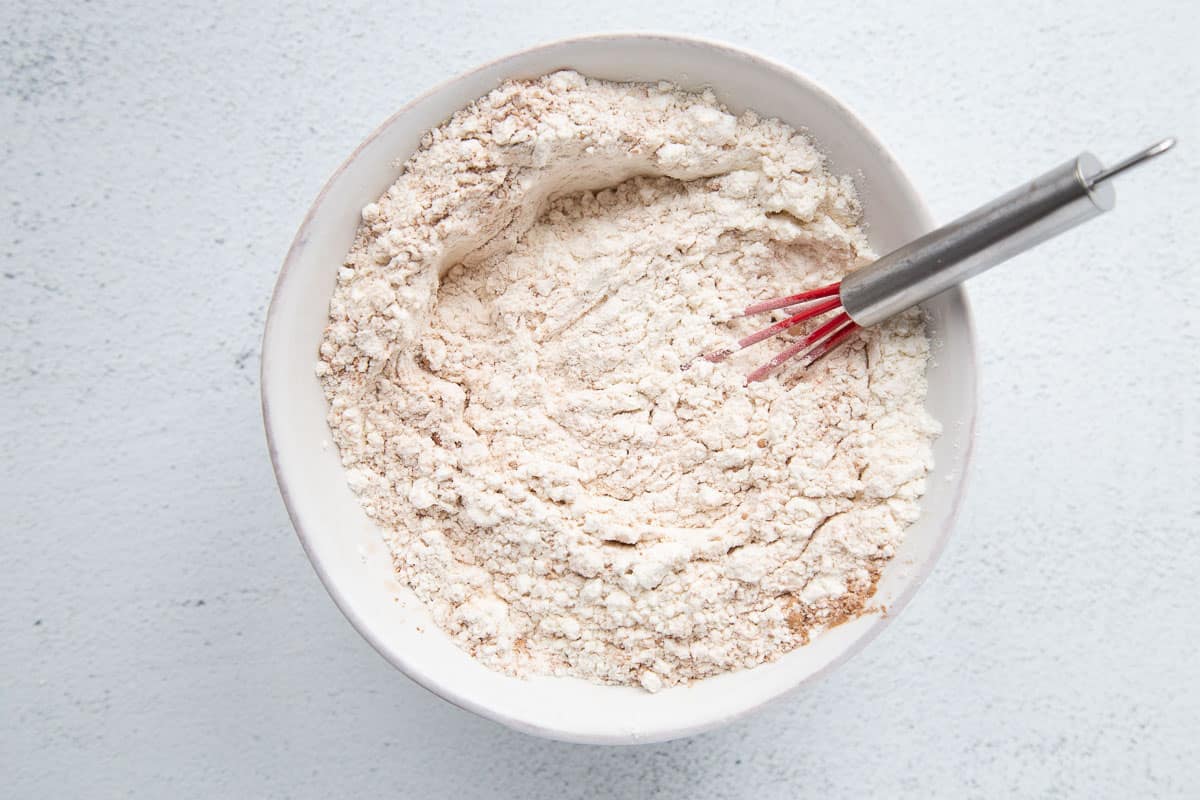 flour mixture in a white bowl with a red whisk.