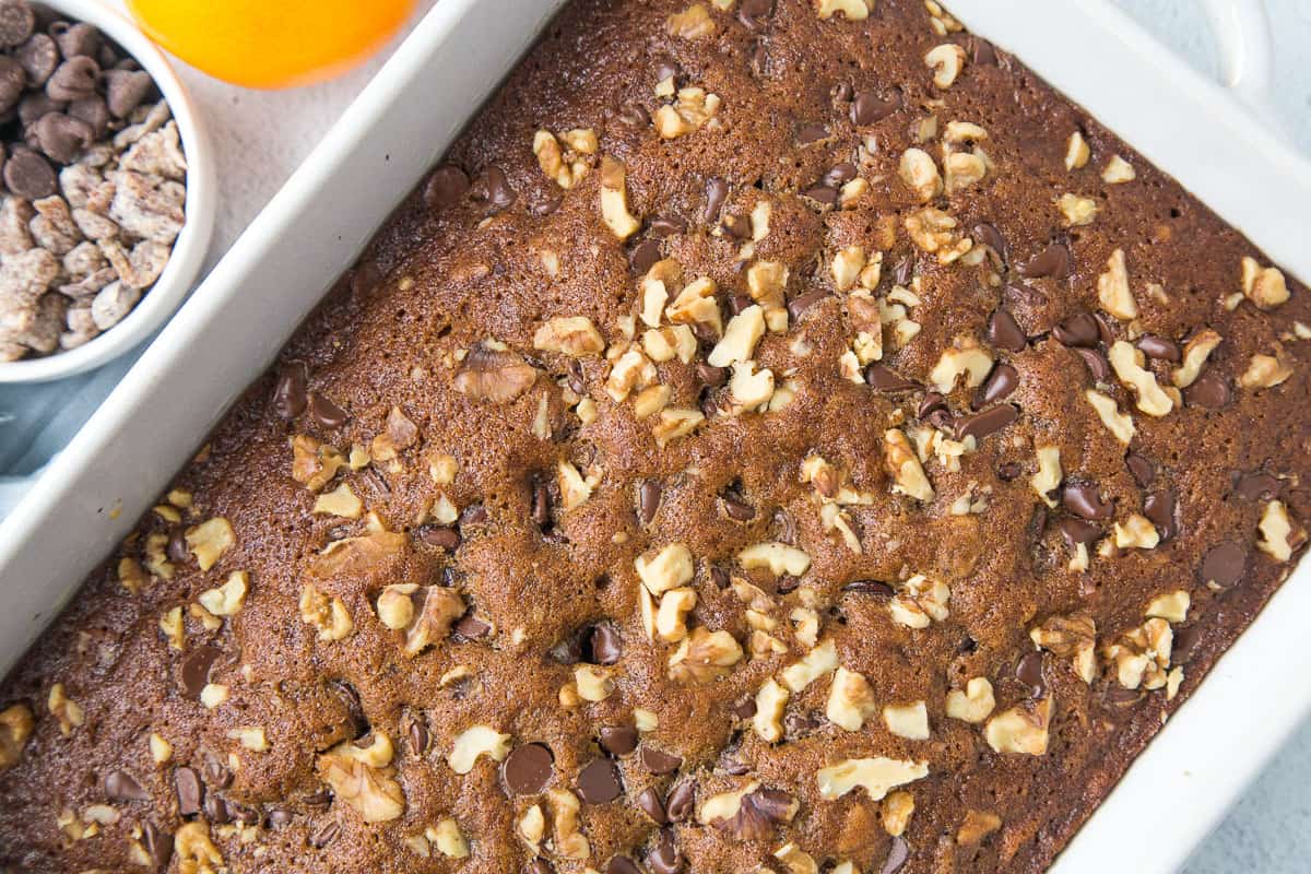 date cake topped with walnuts in a white cake pan.