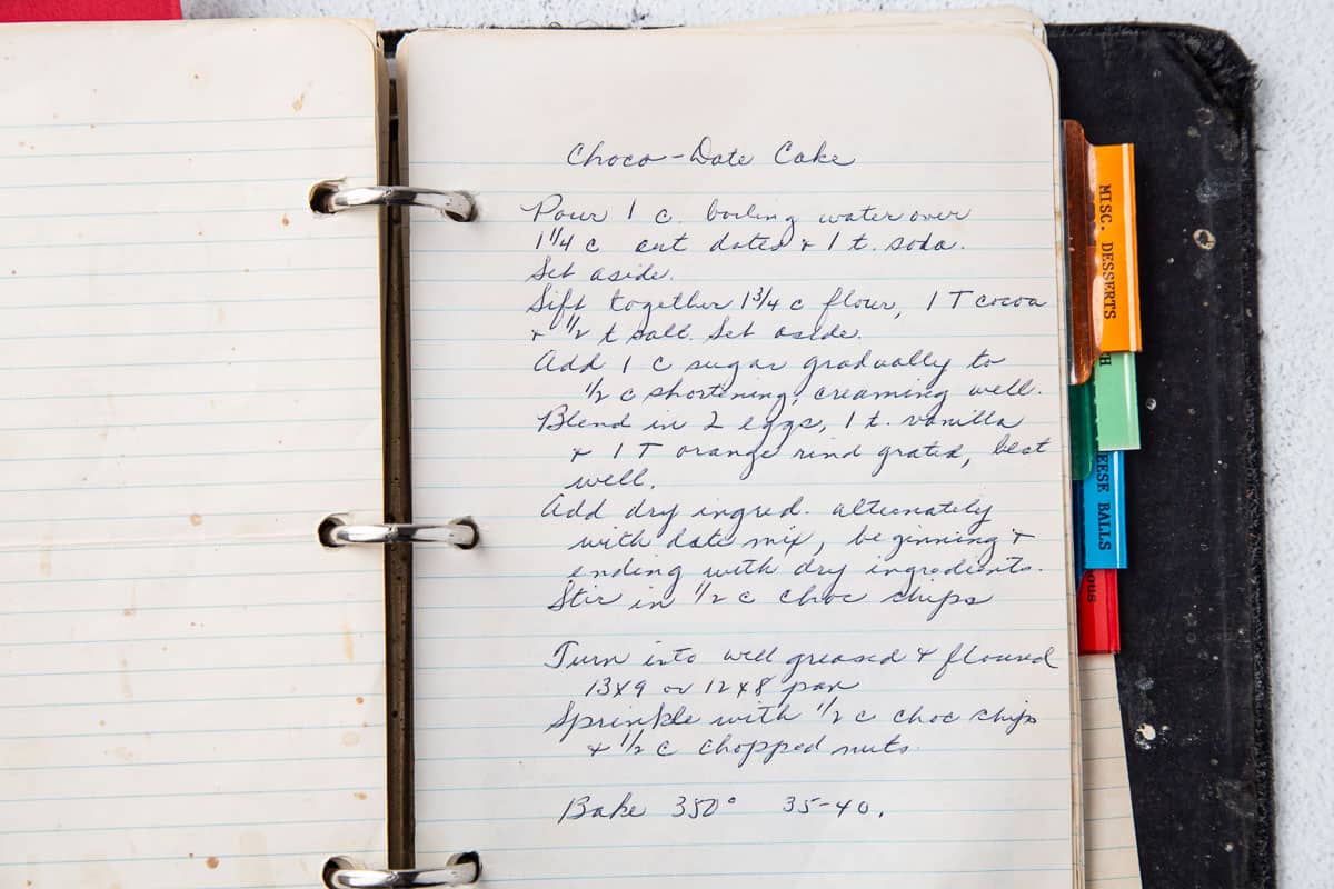 handwritten recipe for date cake on lined paper in an old black recipe binder.