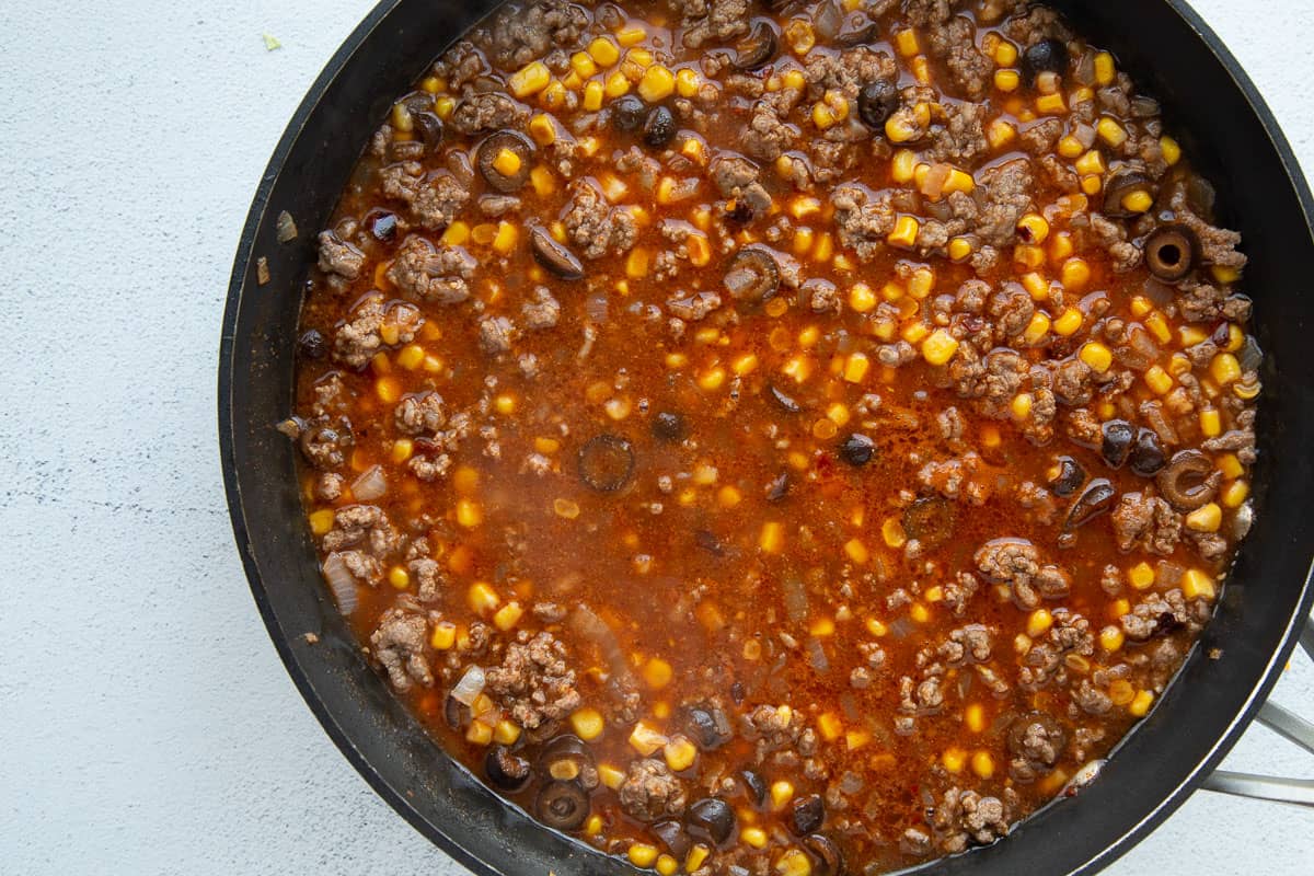 ground beef and corn in a red sauce in a skillet.