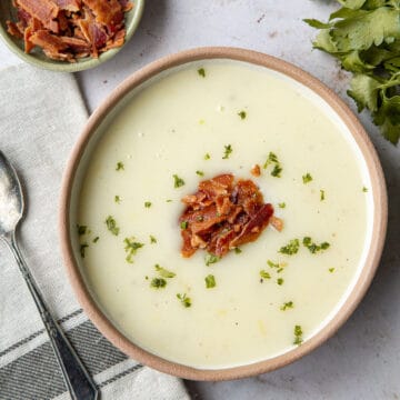 bowl of potato soup topped with chopped bacon and parsley.