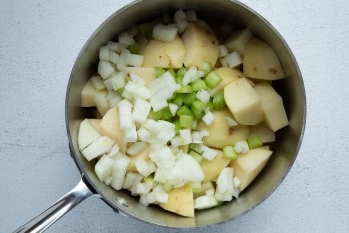 cubed potatoes, chopped onion, and chopped celery in a saucepan.