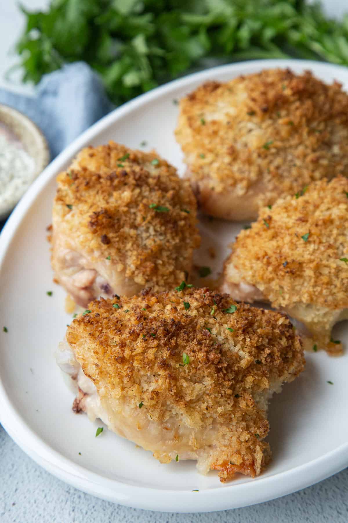 breadcrumb topped ranch chicken thighs on a white platter.