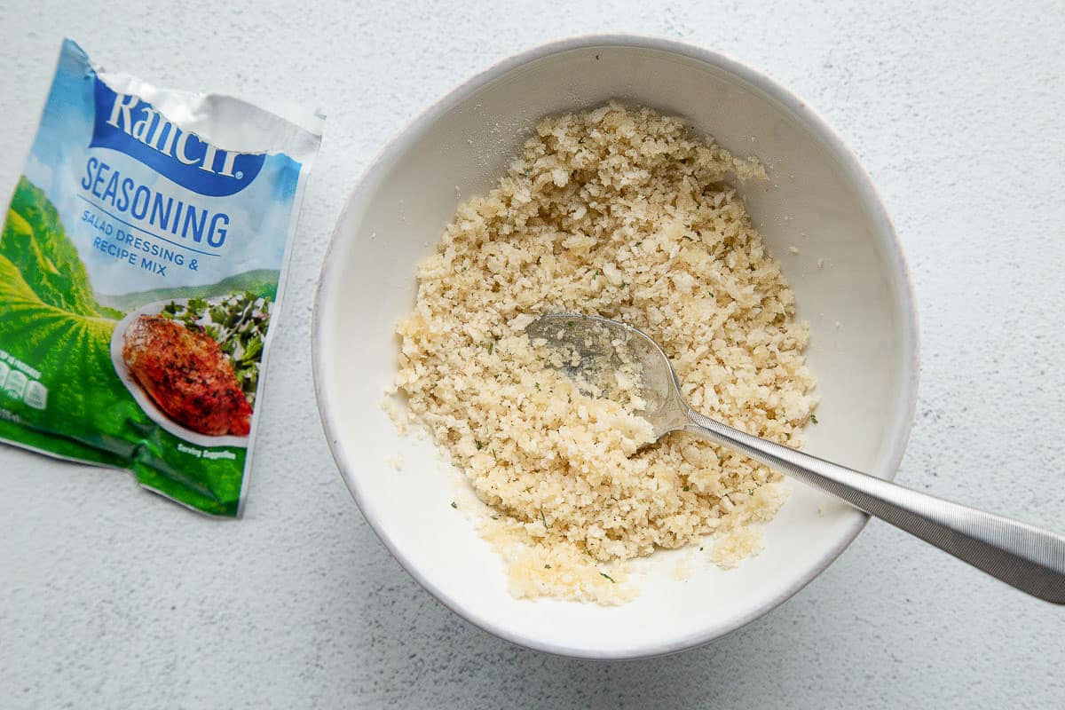 breadcrumbs in a bowl next to a packet of ranch dressing mix.