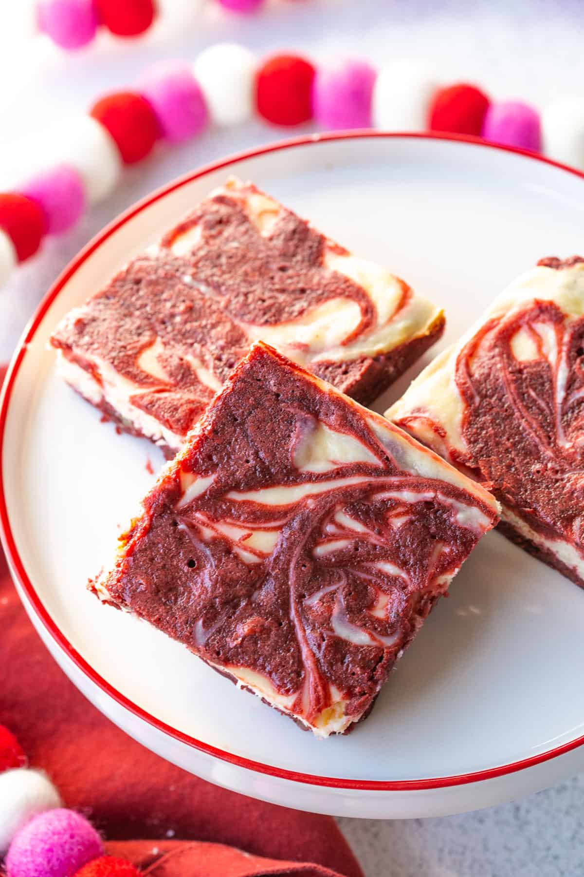 red velvet brownies on a white cake stand with a red rim.