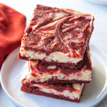 three red velvet brownies stacked on a white plate.