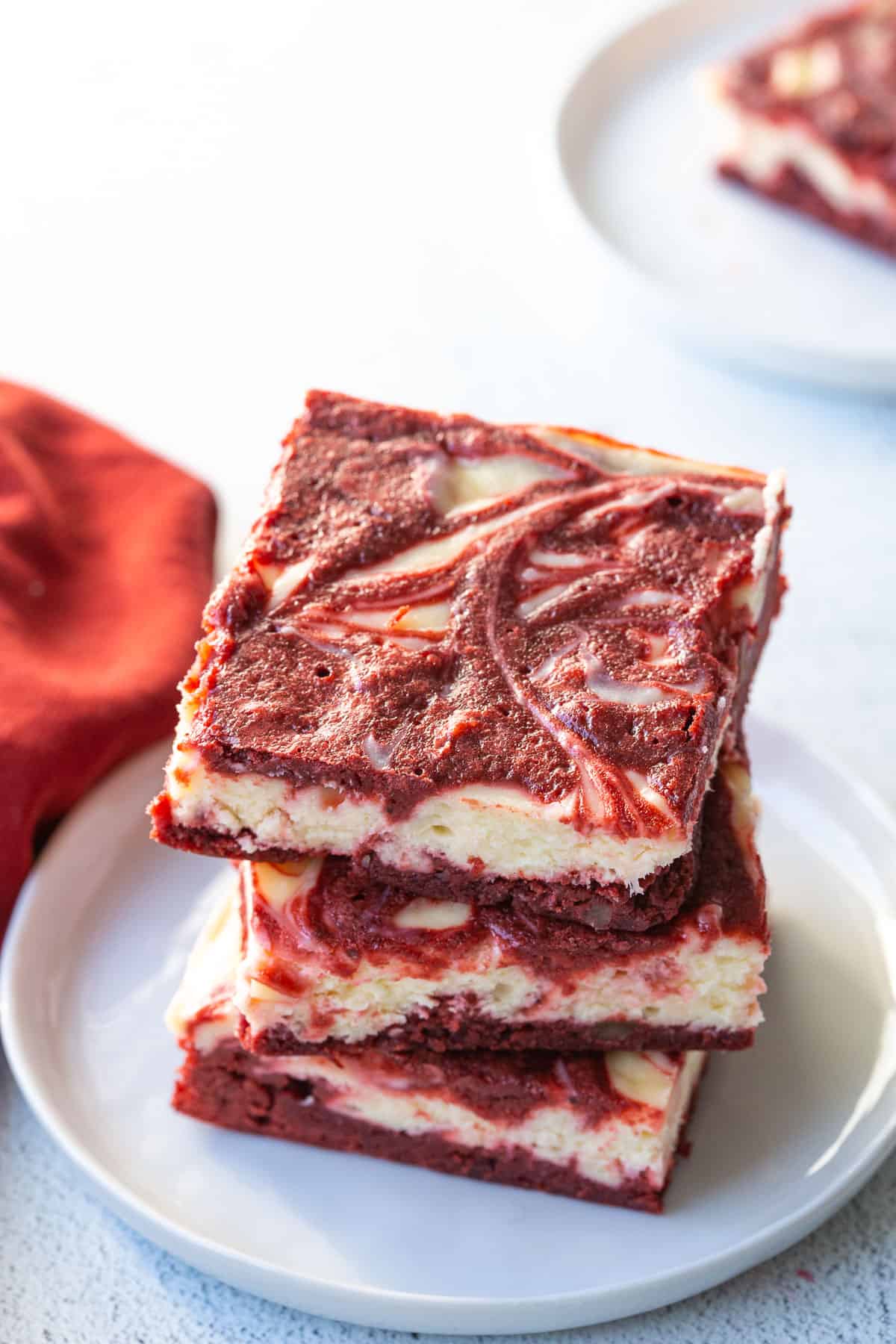 three red velvet brownies stacked on a white plate.