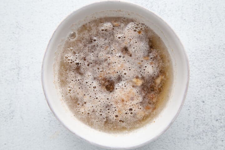chopped dates soaking in water and baking soda in a white bowl.