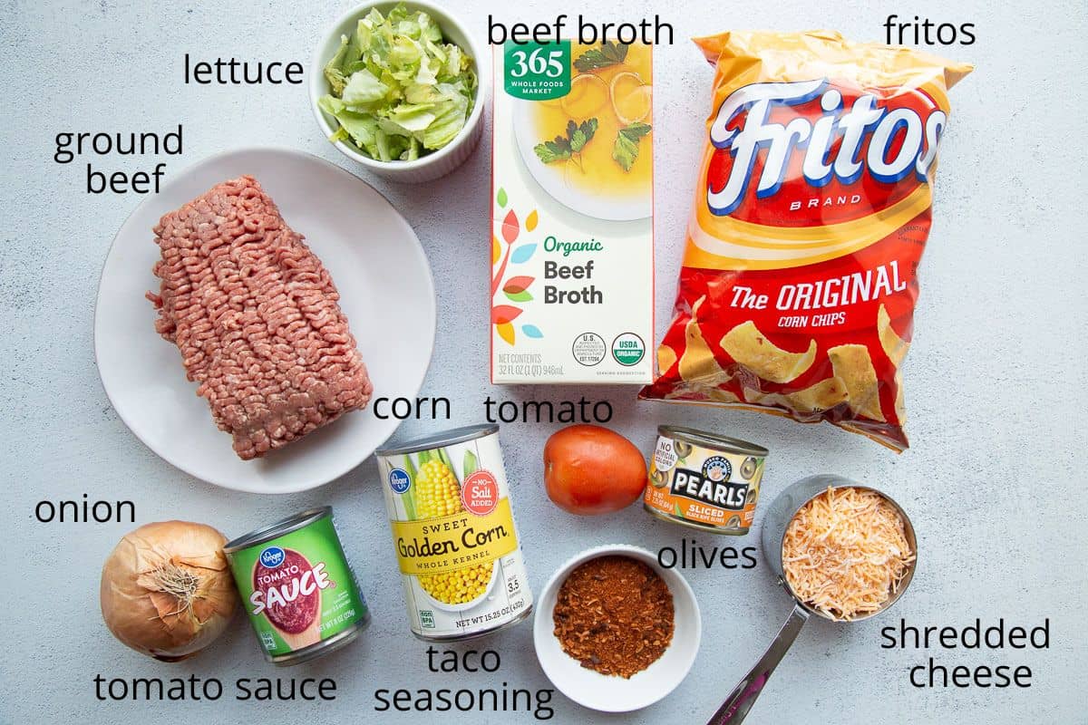 ingredients for taco casserole with fritos on a white table.