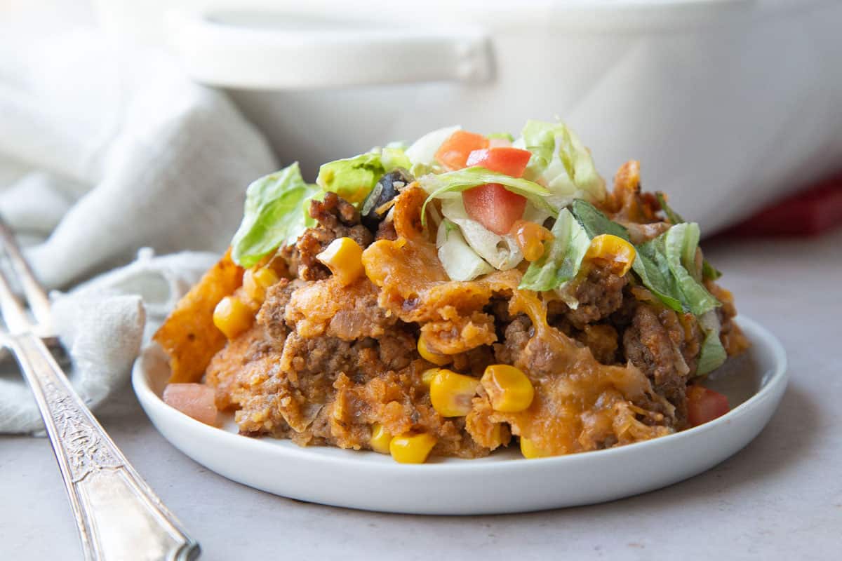 piece of taco casserole on a small white plate next to a fork.